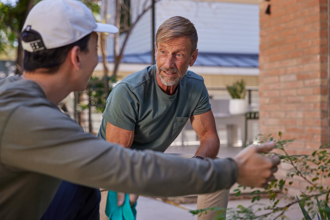 An Aptive Pest Control Specialist Talks With A Homeowner Outside His Home.